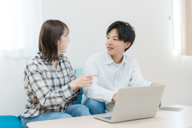 パソコンを見ながら結婚生活について話す男女